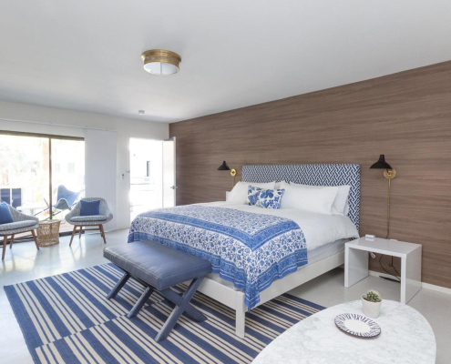 A white bed with blue and white comforter and sheets at Holiday House Palm Springs