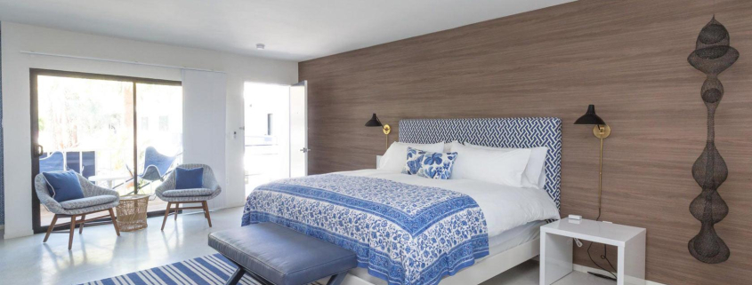 A white bed with blue and white comforter and sheets at Holiday House Palm Springs