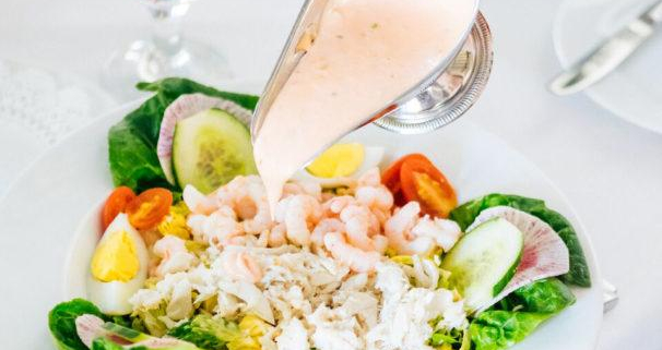A woman pours dressing on her shrimp and crab Louis salad at Ingleside Inn in Palm Springs, California