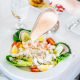 A woman pours dressing on her shrimp and crab Louis salad at Ingleside Inn in Palm Springs, California