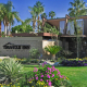 The front entrance of the Triangle Inn men's clothing-optional boutique hotel in Palm Springs, California, has purple and yellow and pink flowers and green grass