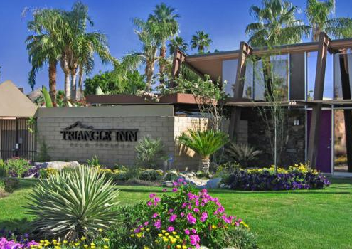 The front entrance of Triangle Inn Palm Springs has a brick wall with its name in large black letters
