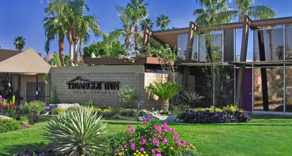 The front entrance of Triangle Inn Palm Springs has a brick wall with its name in large black letters