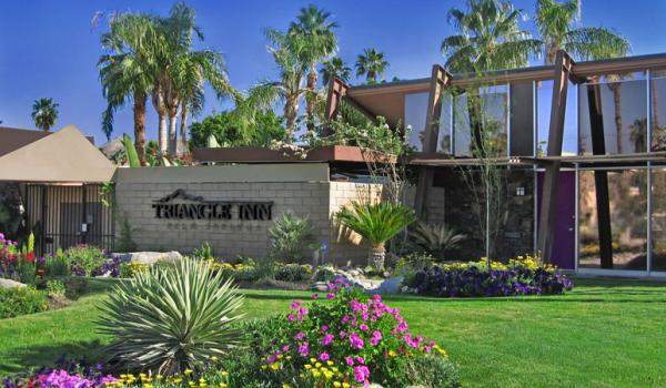 The front entrance of Triangle Inn Palm Springs has a brick wall with its name in large black letters