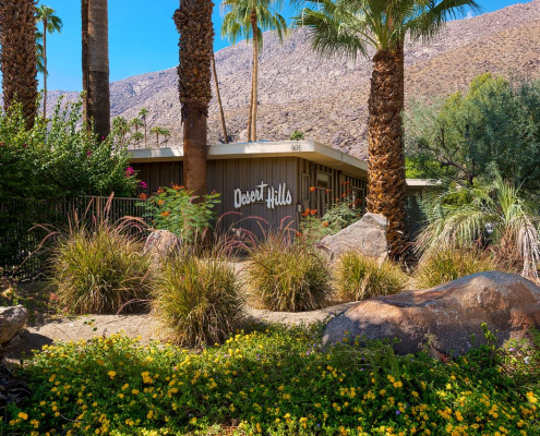 The Desert Hills Resort Hotel exterior with palm trees and native grasses