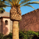 The exterior of Hotel California in Palm Springs, California, with a palm tree in front of it