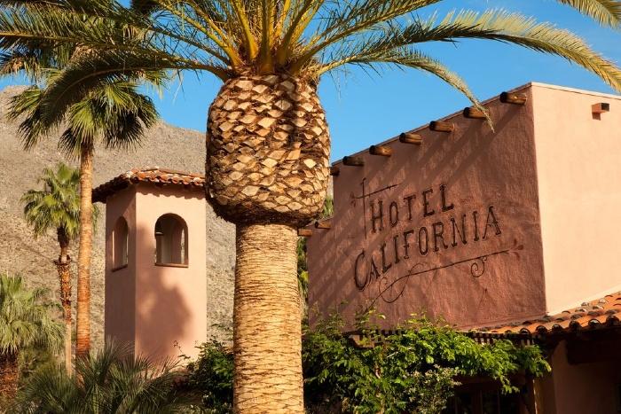 The exterior of Hotel California in Palm Springs, California, with a palm tree in front of it
