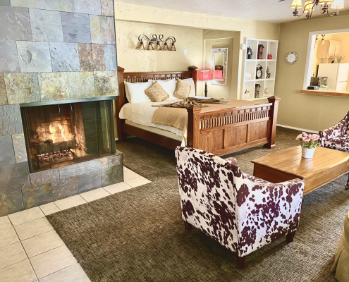 A room at the Old Ranch Inn with a fireplace and cow-print chair and king-sized bed