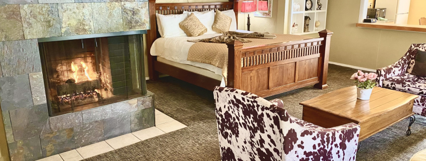 A room at the Old Ranch Inn with a fireplace and cow-print chair and king-sized bed