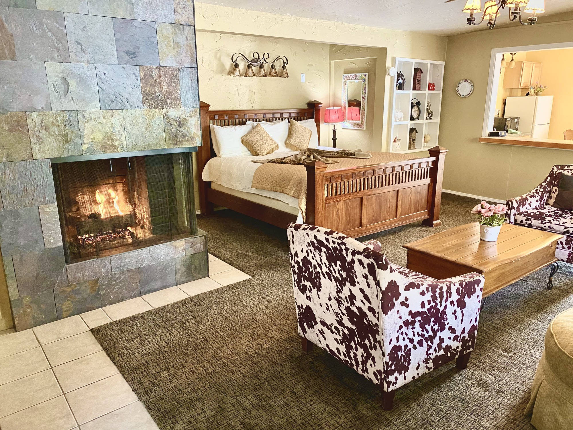 A room at the Old Ranch Inn with a fireplace and cow-print chair and king-sized bed