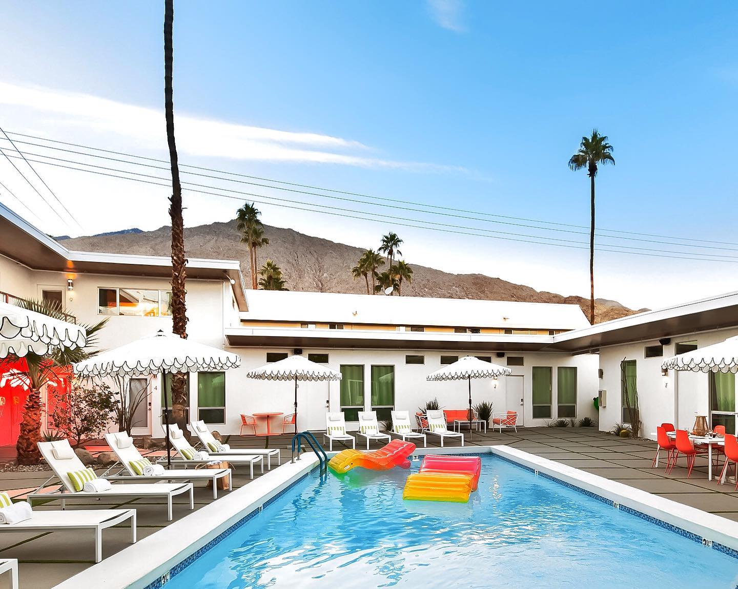 Two colorful rafts float in the courtyard pool on a sunny day at The Wesley Palm Springs hotel