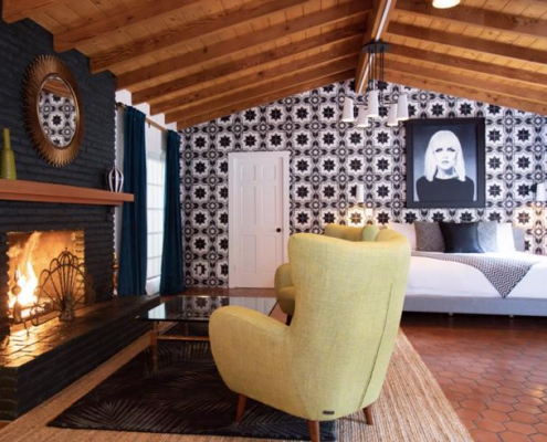 A chair and fireplace in a room at Villa Royale Palm Springs that has a tile wall and hanging picture of Debbie Harry