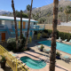 The pool and kidney-shaped spa in the courtyard at Adara Hotel Palm Springs on a sunny day