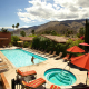 A woman walks out of the pool at the Los Arboles Hotel in Palm Springs, California, on a partly cloudy day