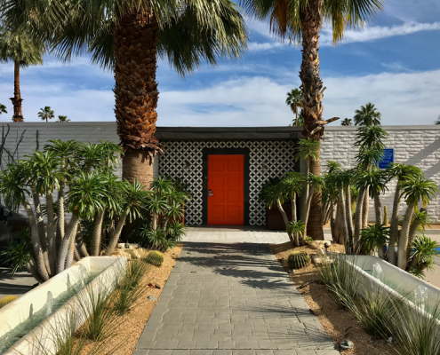 Orange door and white brick entrance to The Weekend Palm Springs mid-century modern hotel in Palm Springs, California