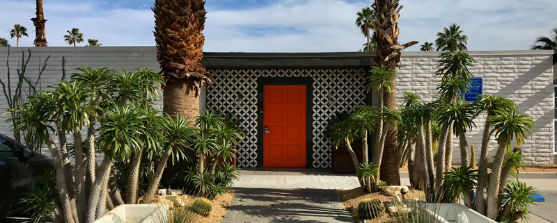 Orange door and white brick entrance to The Weekend Palm Springs mid-century modern hotel in Palm Springs, California