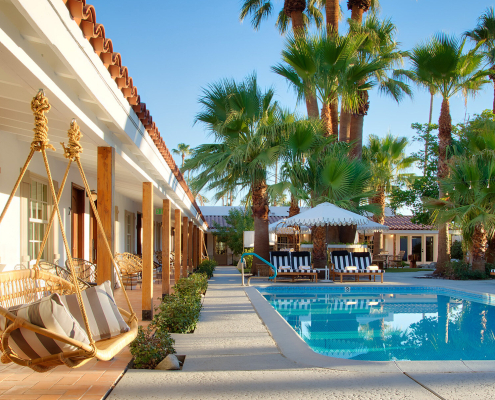 The swimming pool at Dive Palm Springs with swings next to it and palm trees behind it