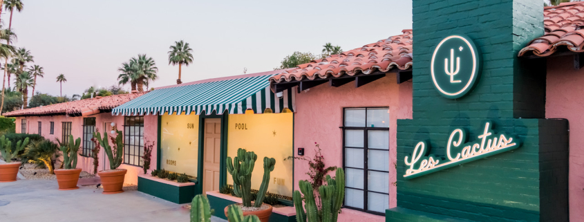 The front entrance to Les Cactus Palm Springs painted green and pink with cacti in pots