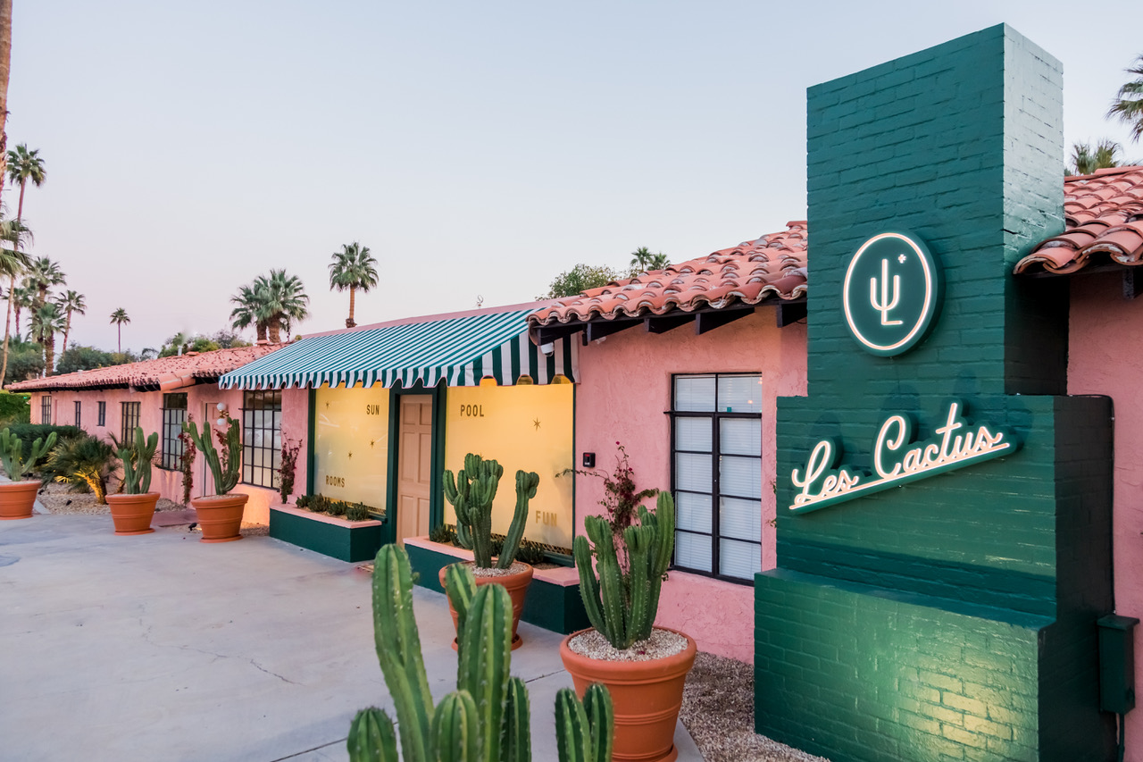 The front entrance to Les Cactus Palm Springs painted green and pink with cacti in pots