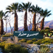 Palm trees flank the old Welcome to Palm Springs sign in Palm Springs, California