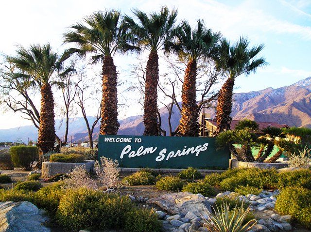 Palm trees flank the old Welcome to Palm Springs sign in Palm Springs, California