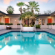 The courtyard pool at The Weekend Palm Springs surrounded by palm trees and the orange doors that lead to individual rooms