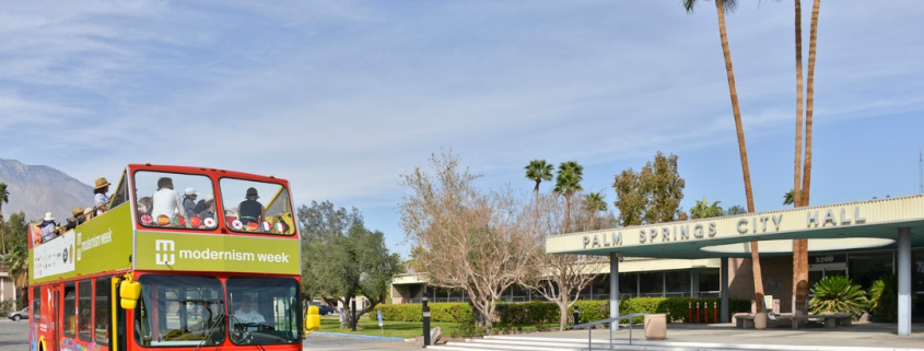A tour bus drives down a street in Palm Springs during Modernism Week