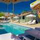 The pool surrounded by white loungers and umbrellas at Fleur Noire Hotel in Palm Springs, California