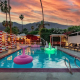 A light up swan pool float in the pool at Float Hotel Palm Springs at dusk with clouds in the sky