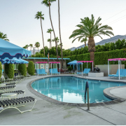 Pink and blue umbrellas and lounge chairs surround the relaxing pool at INNdulge Palm Springs men's clothing-optional resort in Palm Springs, California