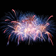 White, blue, and red streaks from fireworks in the night sky