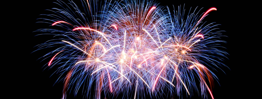 White, blue, and red streaks from fireworks in the night sky