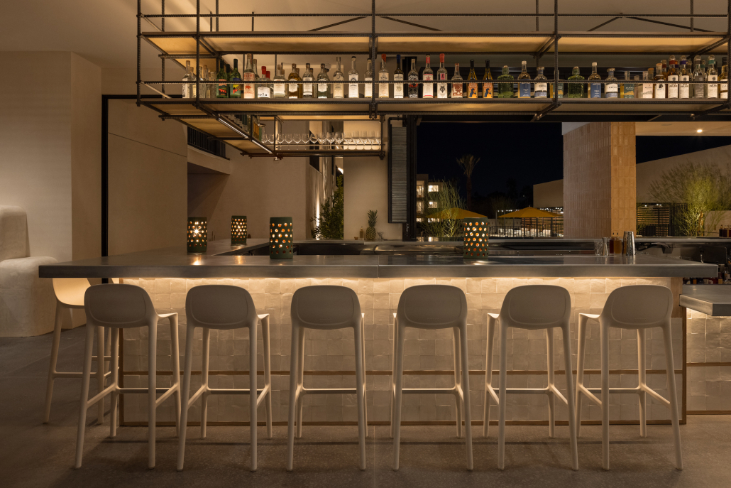 Six white chairs lined up in front of the white bar at Drift Hotel in Palm Springs, California