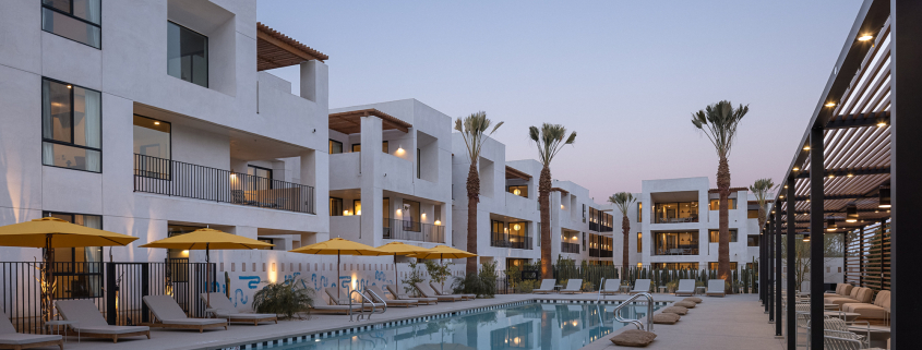 The pool at Drift Palm Springs surrounded by palm trees and loungers and yellow umbrellas