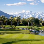 Snow-covered mountains behind a green golf course in Palm Springs, California