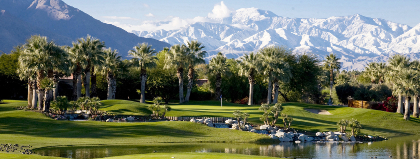 Snow-covered mountains behind a green golf course in Palm Springs, California