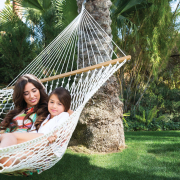 A woman and girl sit in a hammock outside