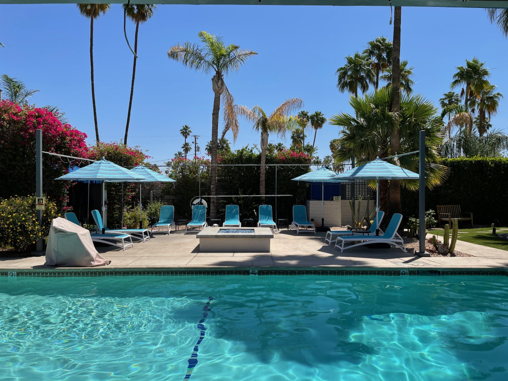 A pool surrounded by blue umbrellas and chairs