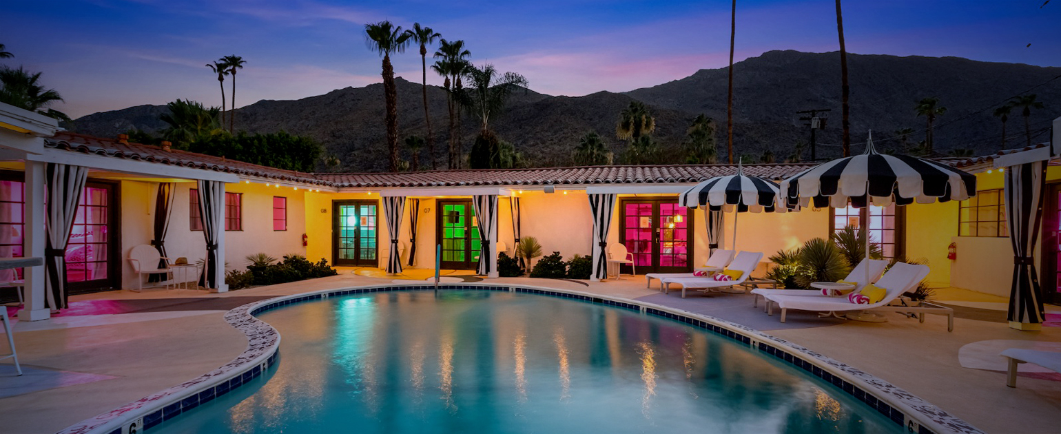 The pool at Spirit of Sofia in Palm Springs, California, surrounded by rooms with colored lights in the windows
