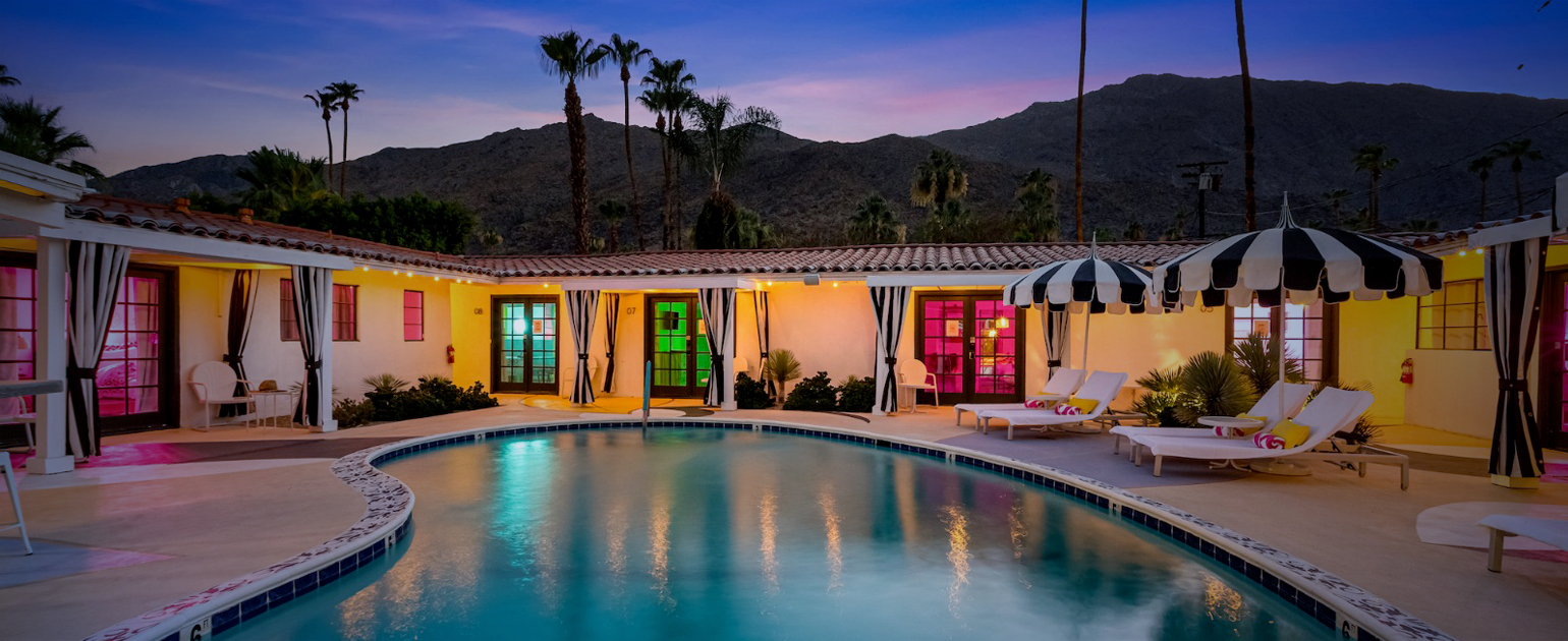 The pool at Spirit of Sofia in Palm Springs, California, surrounded by rooms with colored lights in the windows