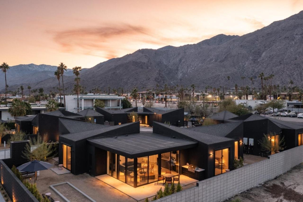 An aerial view of the four black buildings that make up Blackhaus with the San Jacinto Mountains in the background