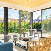 A room with a blue couch and floor to ceiling glass windows that show palm trees outside