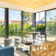 A room with a blue couch and floor to ceiling glass windows that show palm trees outside