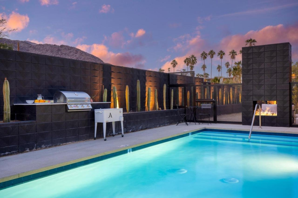 The pool and barbecue area of Blackhaus at sunset with pink clouds and palm trees in the background