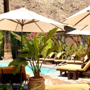 White umbrellas shade lounge chairs poolside at Talavera Palm Springs