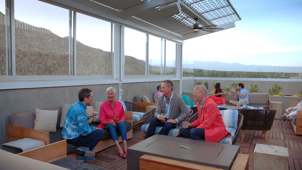 A group of four adults it outside under a fan in Palm Springs, California