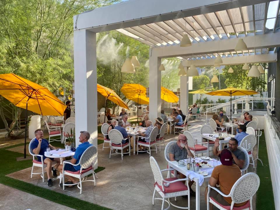 Groups of diners eat under yellow umbrellas at Eight4Nine in Palm Springs, California