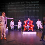 A white man points at a Black man while on stage performing "Gross Indecency" in Palm Springs