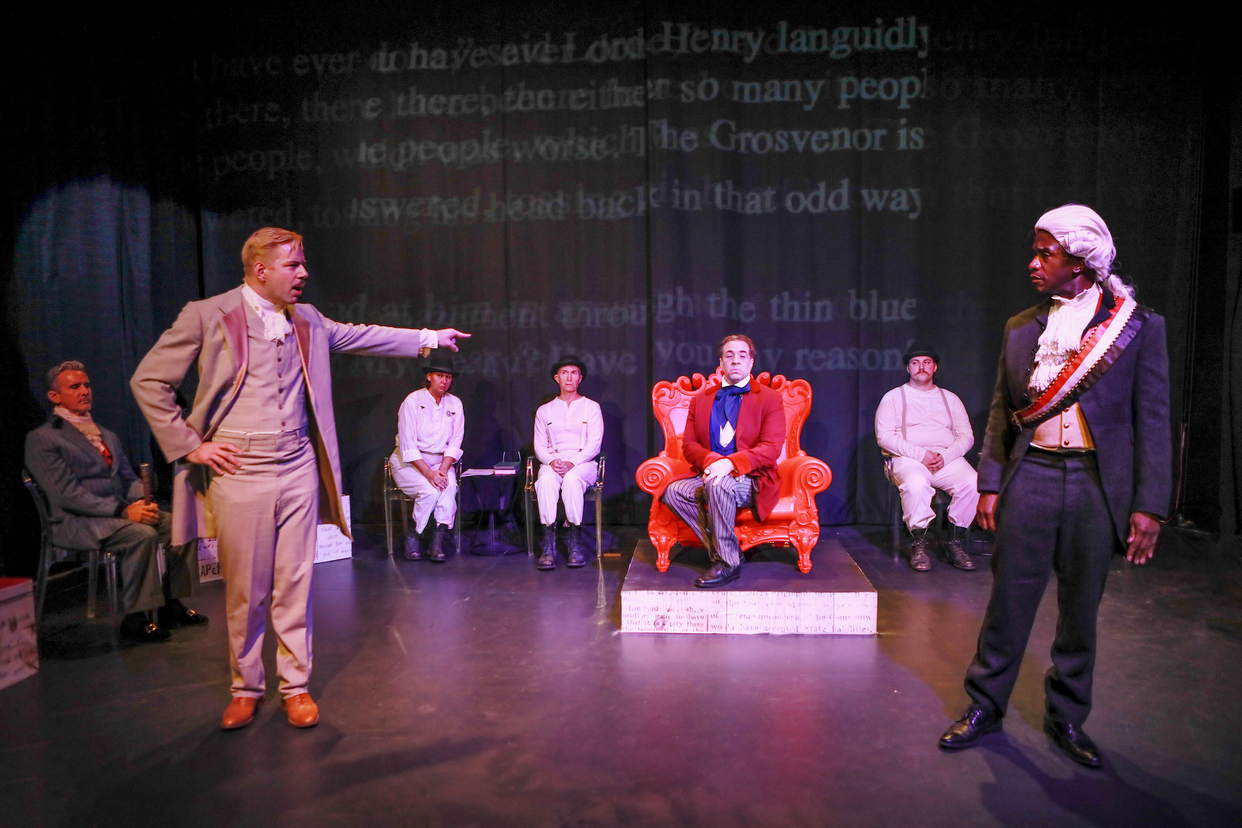 A white man points at a Black man while on stage performing "Gross Indecency" in Palm Springs