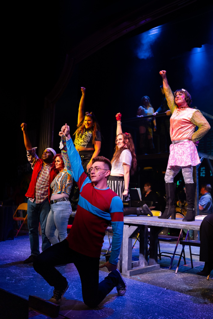 Six "RENT" cast members hold their fists up while on stage a the Palm Canyon Theater in Palm Springs, California